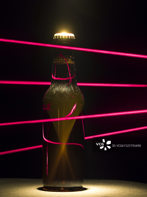 被红色激光束陷阱保护的啤酒瓶图片素材