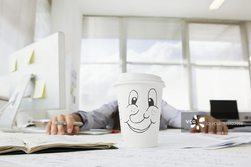 疲惫的商人趴在办公桌上，面前放着外卖咖啡图片素材