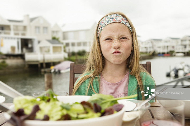 在桌子旁做鬼脸的女孩肖像（8-9岁）图片素材