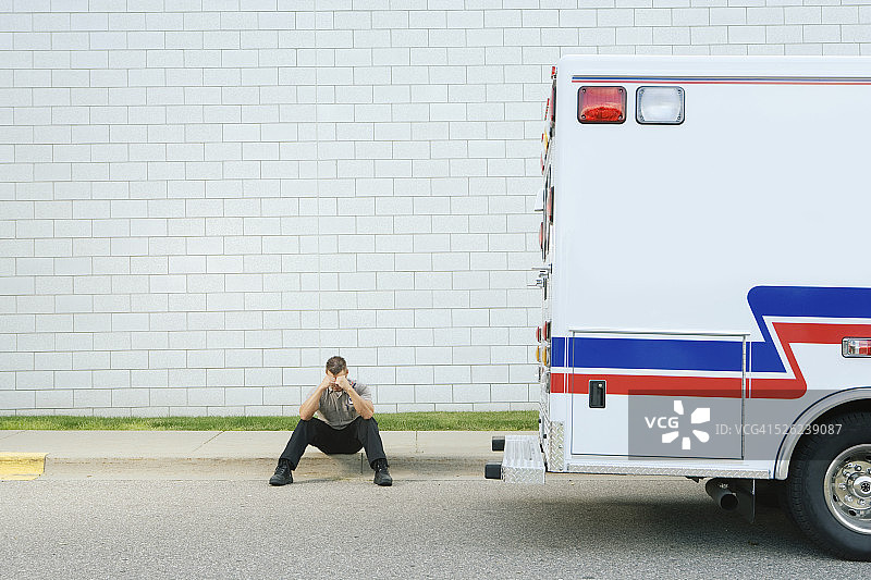 急救人员坐在人行道上，双手抱头图片素材