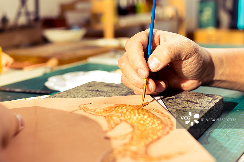 皮革工匠在皮革上绘制鱼图案图片素材