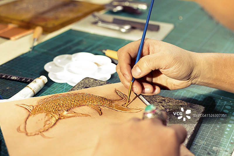 皮革工匠在皮革上绘制鱼图案图片素材