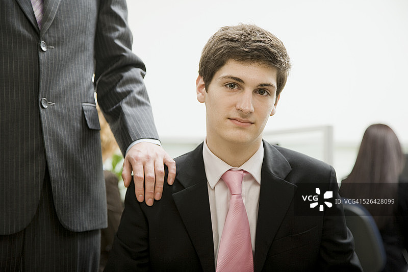 男子坐在办公室里，老板在他身后图片素材