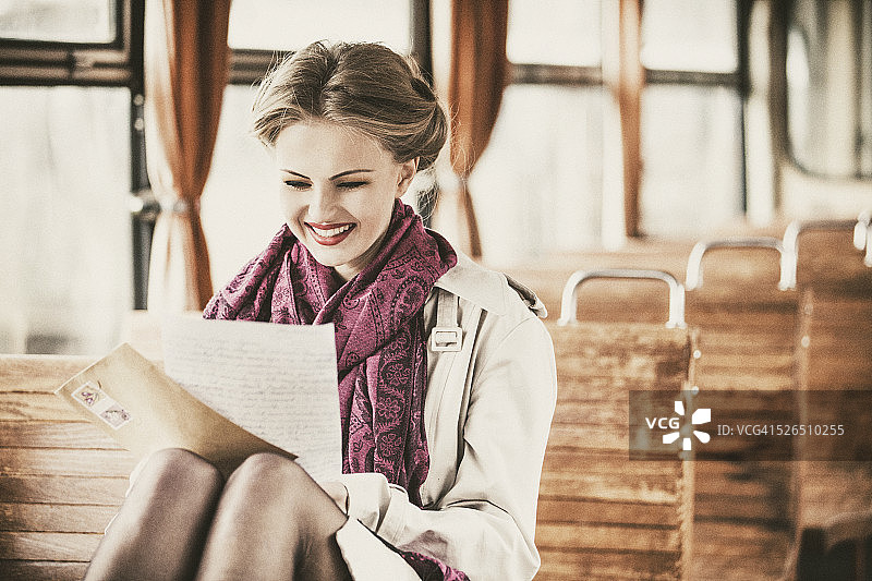 年轻女子在复古火车车厢里读信图片素材