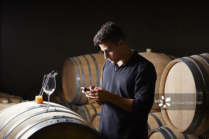 葡萄酒专家在智能手机上做笔记图片素材