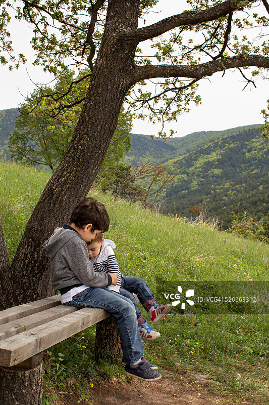 兄弟俩坐在木凳上拥抱图片素材