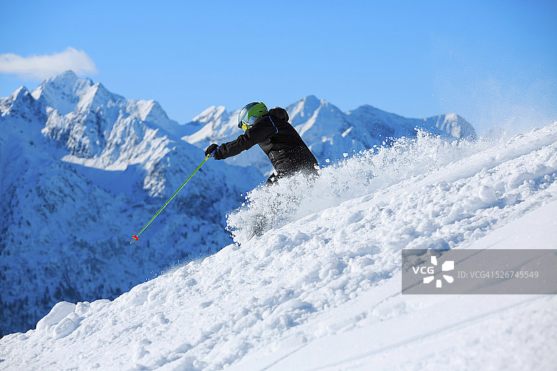 男人们在阳光明媚的滑雪胜地进行野雪粉雪滑雪图片素材