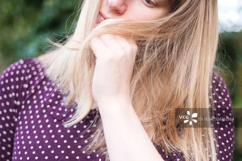 若有所思地摆弄头发的金发女人图片素材