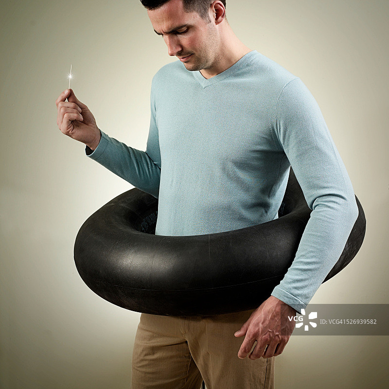 男人戴游泳圈手持针，影棚拍摄图片素材