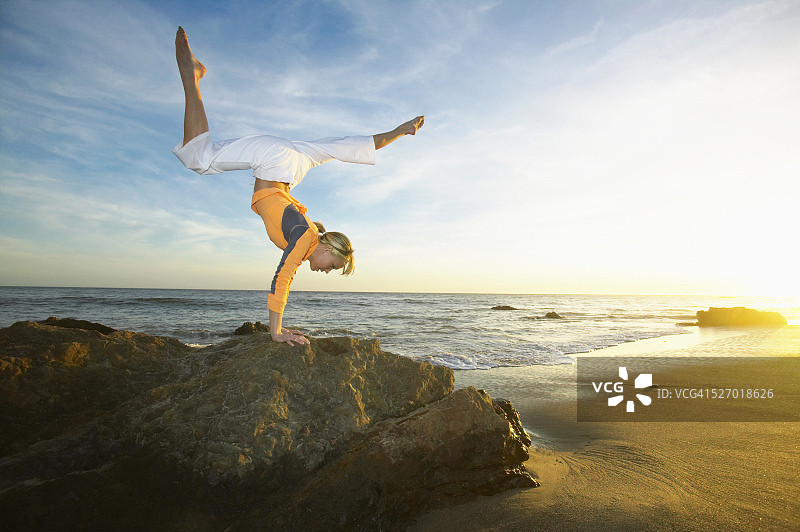 在岩石顶端做倒立的女人图片素材