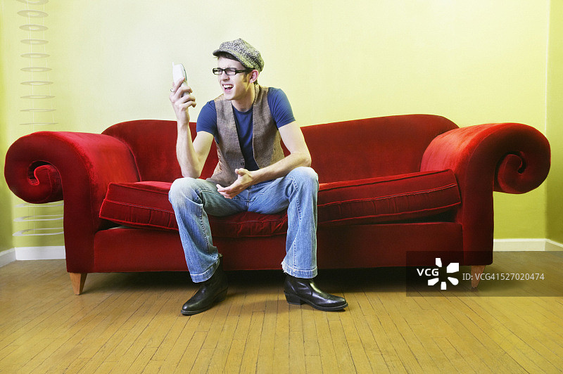 沮丧的男人坐在沙发上打电话图片素材