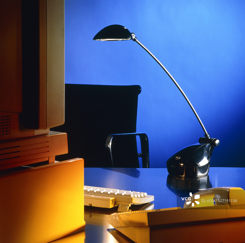 配有电脑、台灯和电话的办公桌，蓝色灯光图片素材