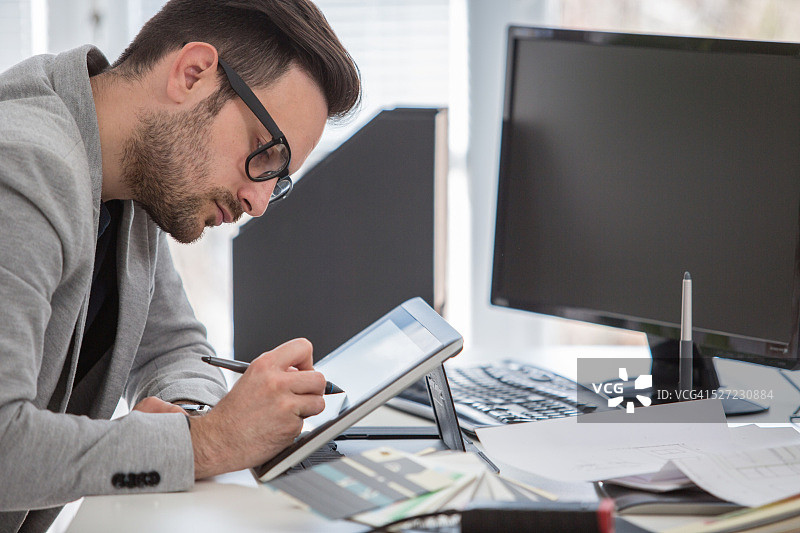 在创意办公室使用绘图板的年轻职业人士图片素材