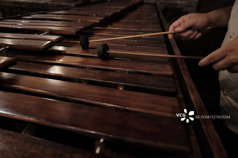 在危地马拉，一人手持木槌敲击旧木制马林巴琴的琴键图片素材