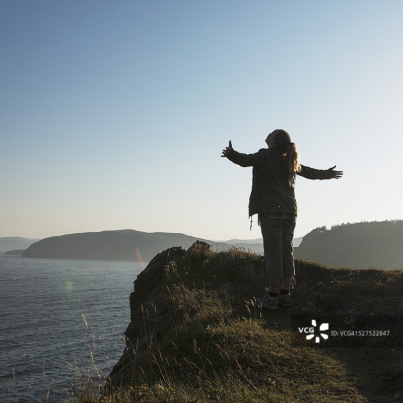 年轻女子站在山脊上，张开双臂眺望大西洋图片素材