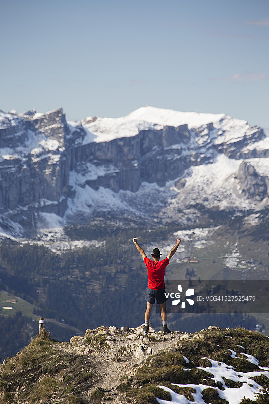 站在山顶，眺望远处雪山的男人图片素材