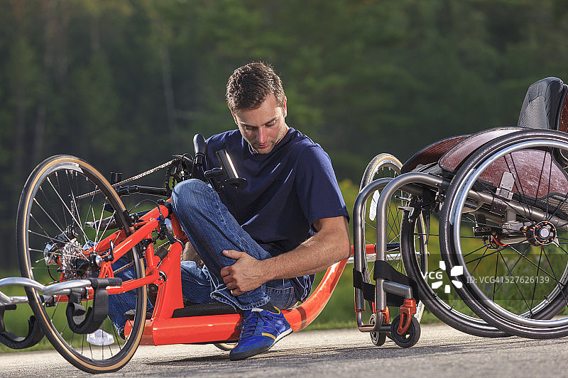 坐在定制的自适应手摇车中的脊髓损伤男子进入轮椅图片素材