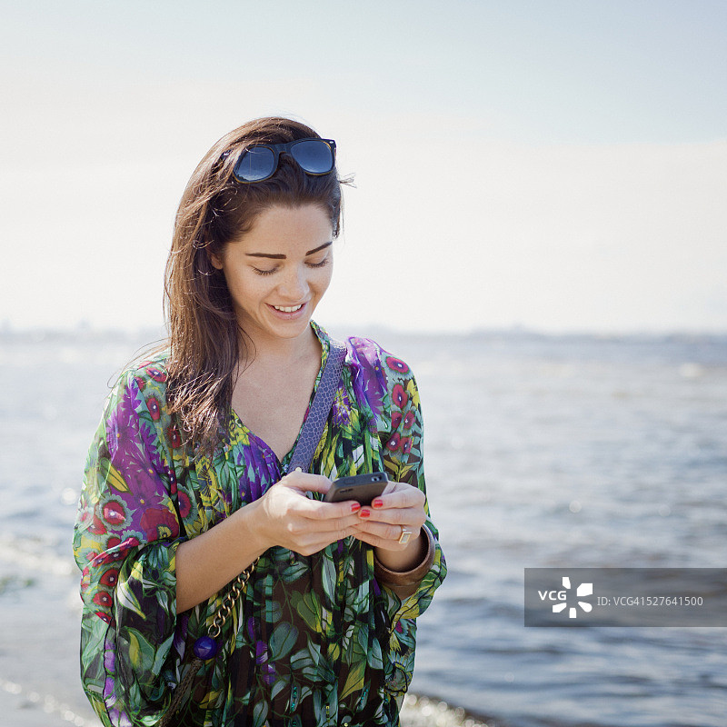在海滩上发短信的女子图片素材