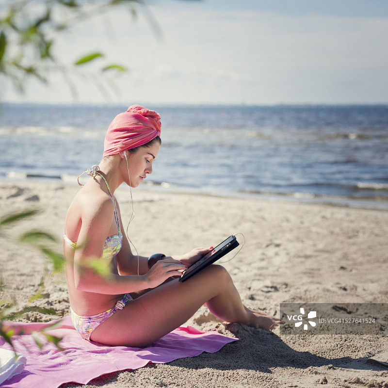 在沙滩上用电脑工作的比基尼女子图片素材