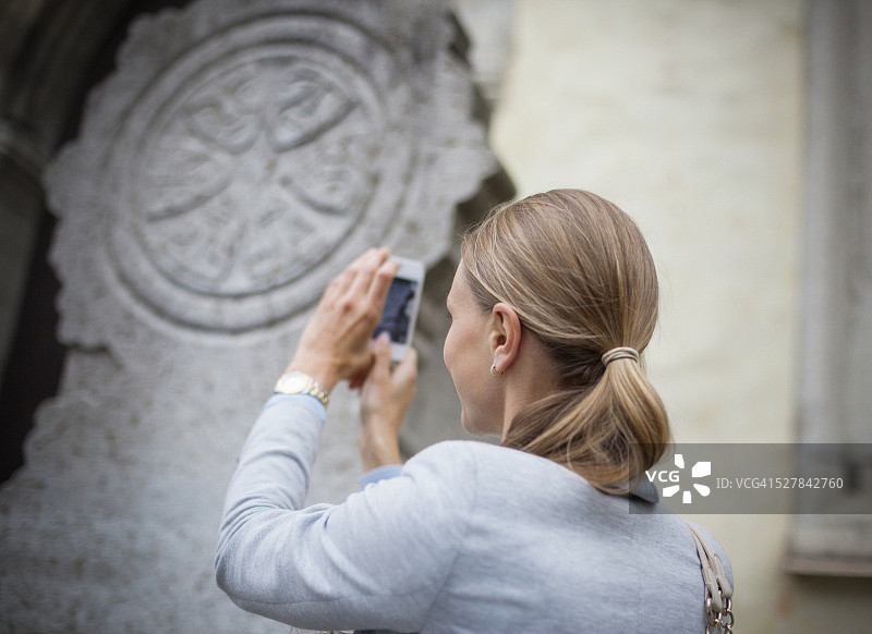 在爱沙尼亚塔林用智能手机拍照的年轻女人图片素材