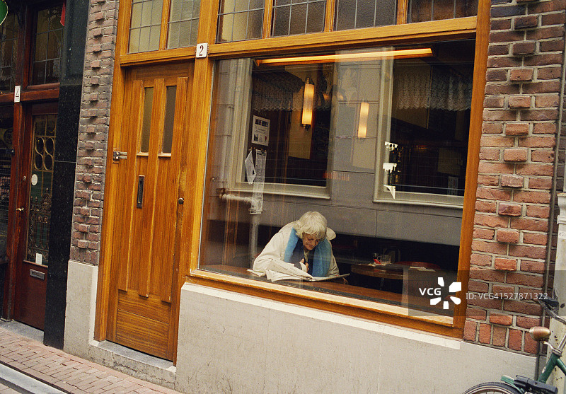 在咖啡馆阅读的老年妇女图片素材