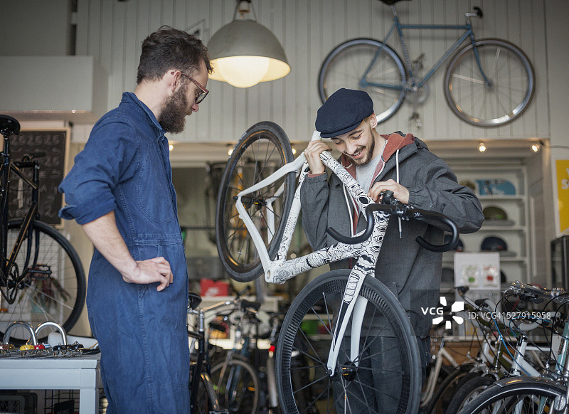 顾客和修理工在自行车店检查超轻型自行车图片素材