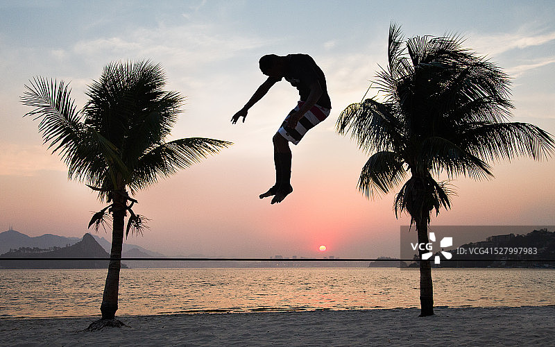年轻男人在棕榈树之间走扁带图片素材