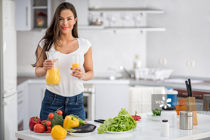 在厨房里拿着橙汁的女人图片素材