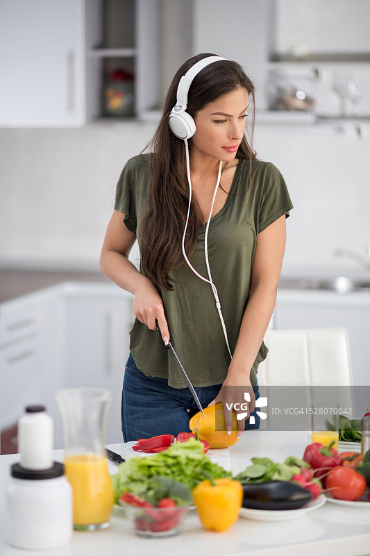戴着耳机切甜椒的女人图片素材