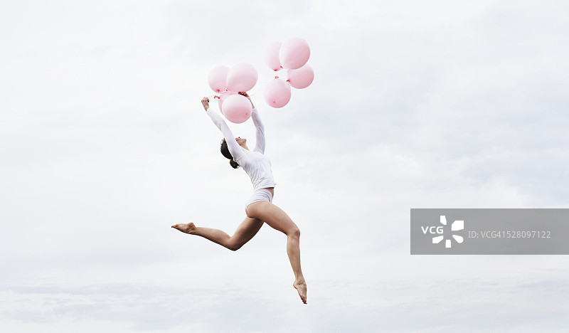 手持粉色气球高高跳跃的舞者图片素材