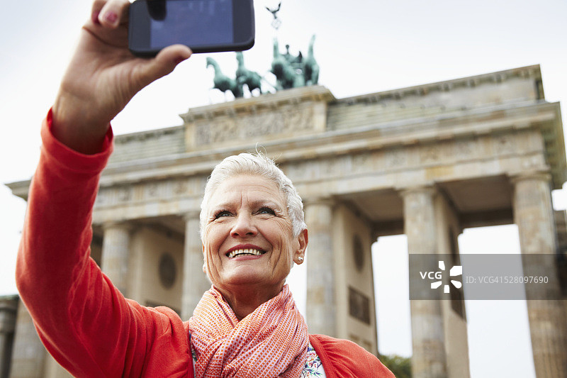 柏林勃兰登堡门前一个快乐和满足的年长妇女的肖像。图片素材