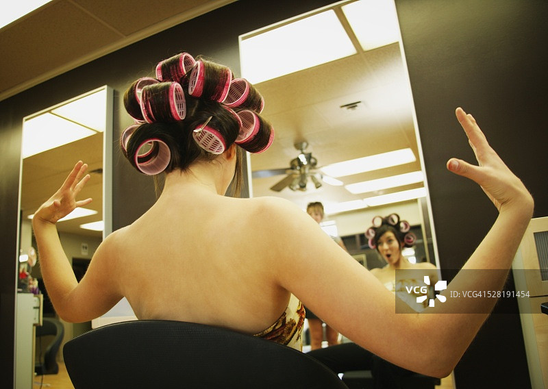 震惊的带卷发器的年轻女子图片素材