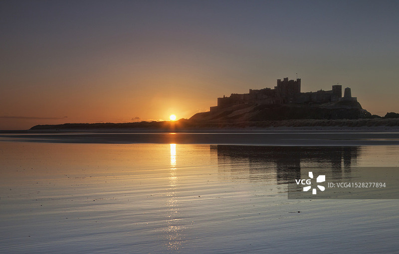日落时分倒映在水中的班堡城堡；英格兰诺森伯兰郡班堡图片素材