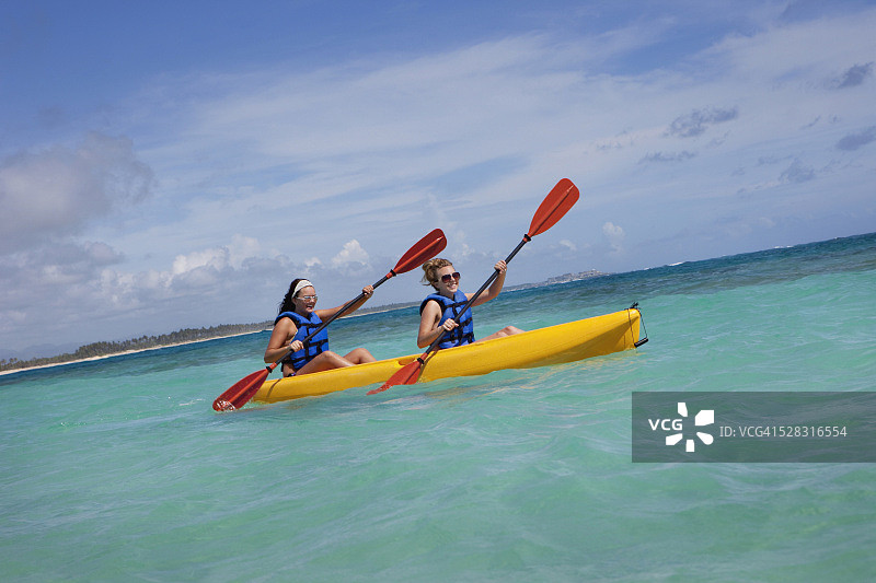 穿着救生衣在黄色船上划桨的两个女人图片素材