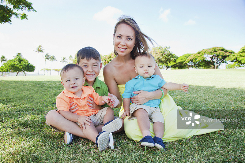 和三个儿子坐在夏威夷瓦胡岛檀香山草地公园里的单身母亲图片素材