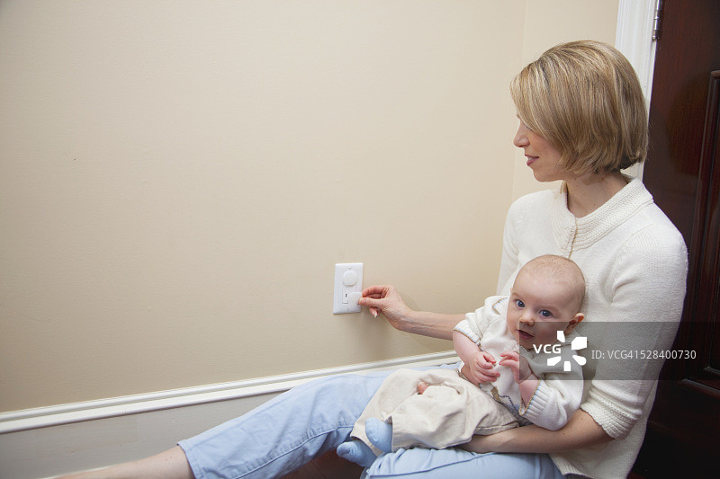母亲带着宝宝在插座上使用安全塞；加拿大的安大略省图片素材