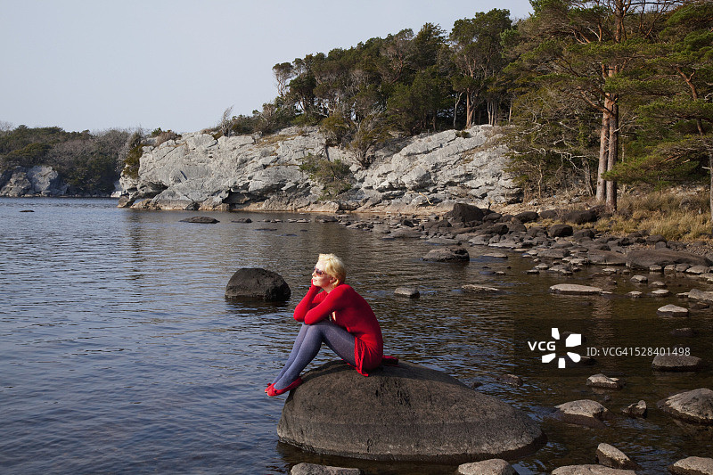 年轻女人坐在爱尔兰麦克罗斯湖的大石头上图片素材