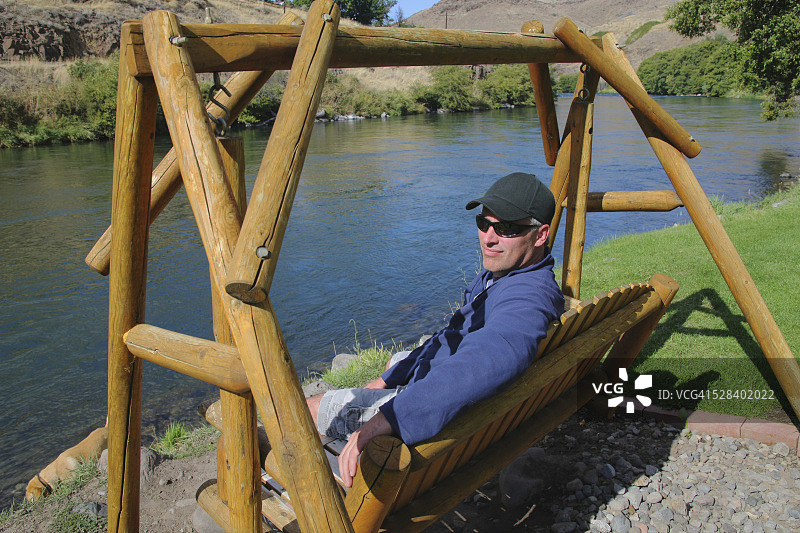 一名男子坐在俄勒冈州莫平水边的秋千上图片素材