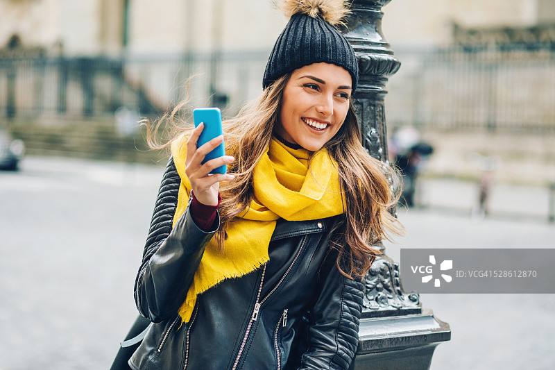 在巴黎手持手机的微笑年轻女人图片素材