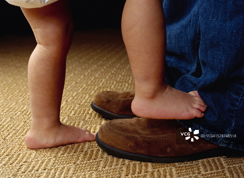 幼儿踩在成人的鞋子上图片素材