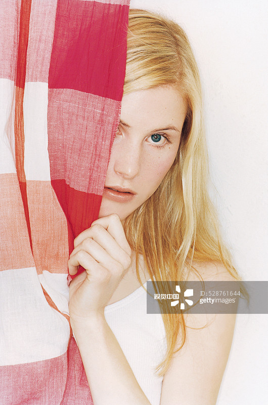 窗帘后的年轻女子图片素材