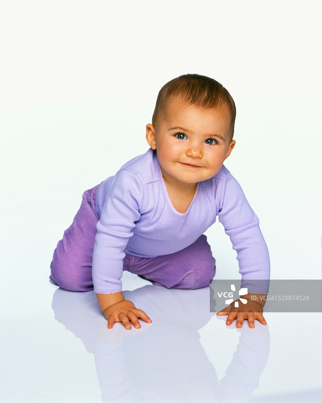 穿着紫色衣服的爬行幼儿图片素材