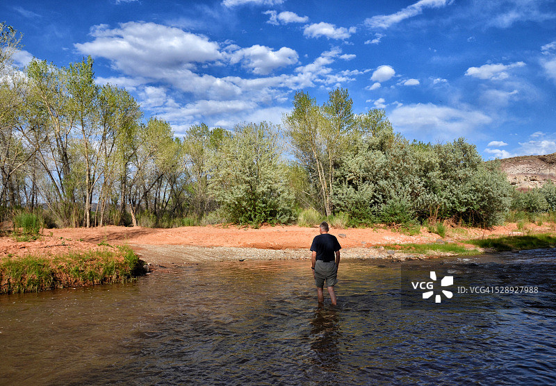 男子穿越弗里蒙特河，犹他州圆顶礁国家公园图片素材