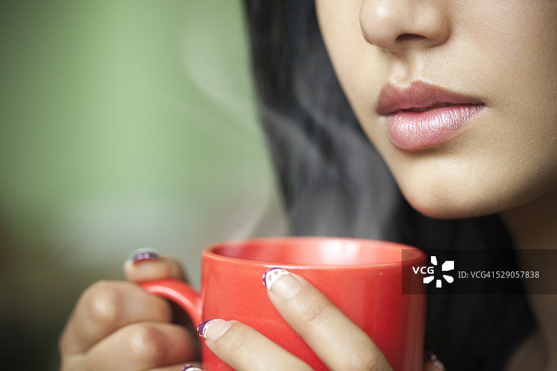 手持热咖啡的年轻女子（局部特写）图片素材