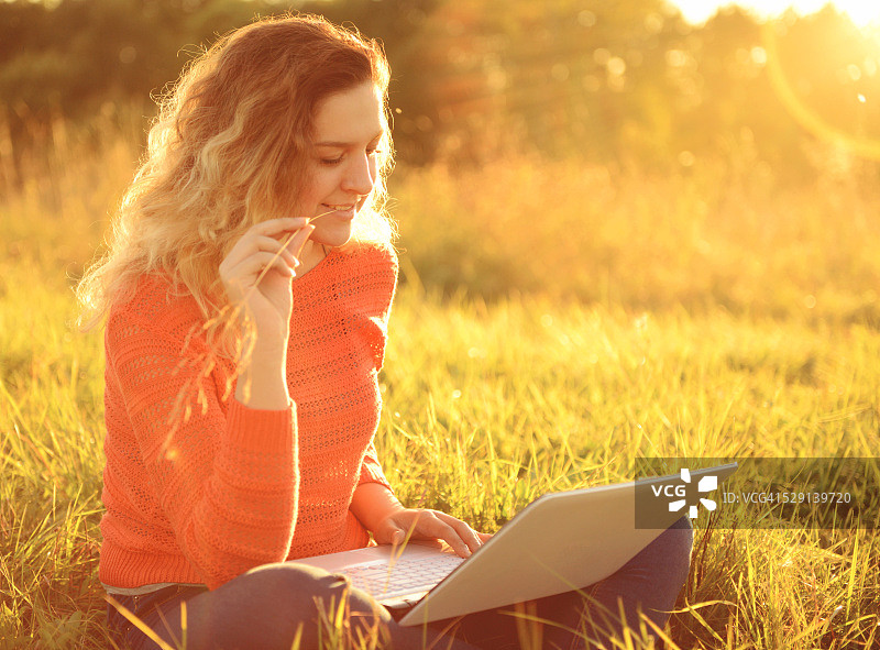 在户外使用笔记本电脑的年轻漂亮女孩图片素材