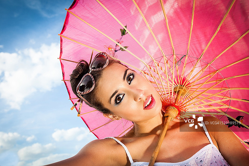 拿着红色雨伞和戴太阳镜的年轻女人图片素材