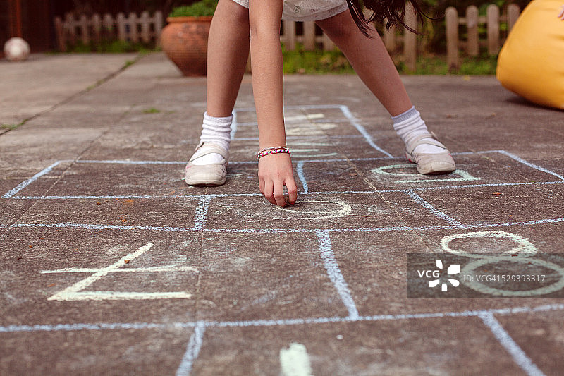 玩跳房子的女孩，低角度拍摄图片素材