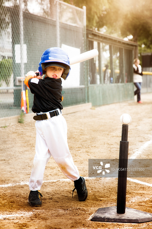 小男孩在T座上练习棒球挥杆图片素材
