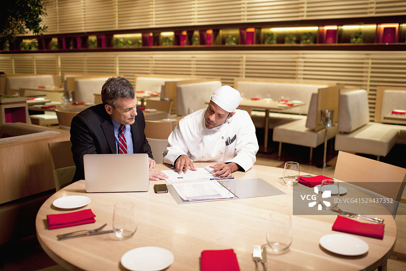餐厅里，店主和厨师在桌旁交谈图片素材