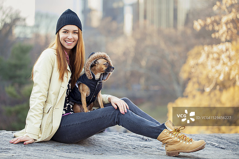 快乐的年轻女人和她的搜救犬在城市公园里图片素材